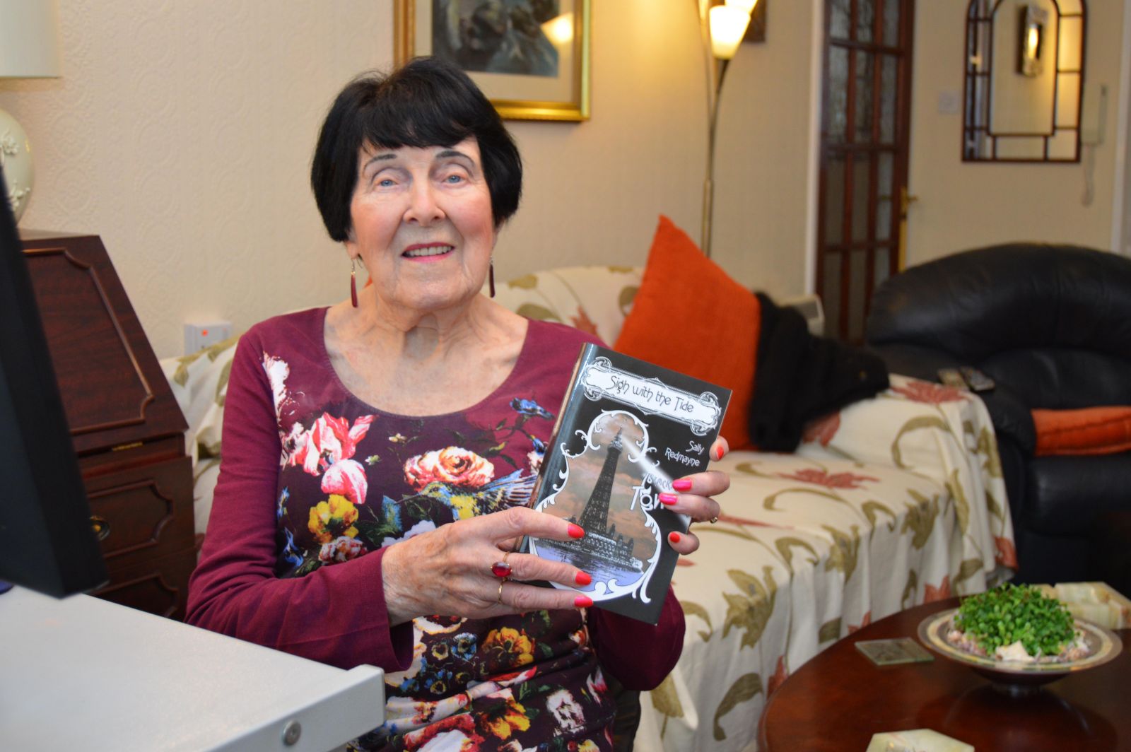 Freda pictured with a copy of her published novel, Sigh With The Tide.